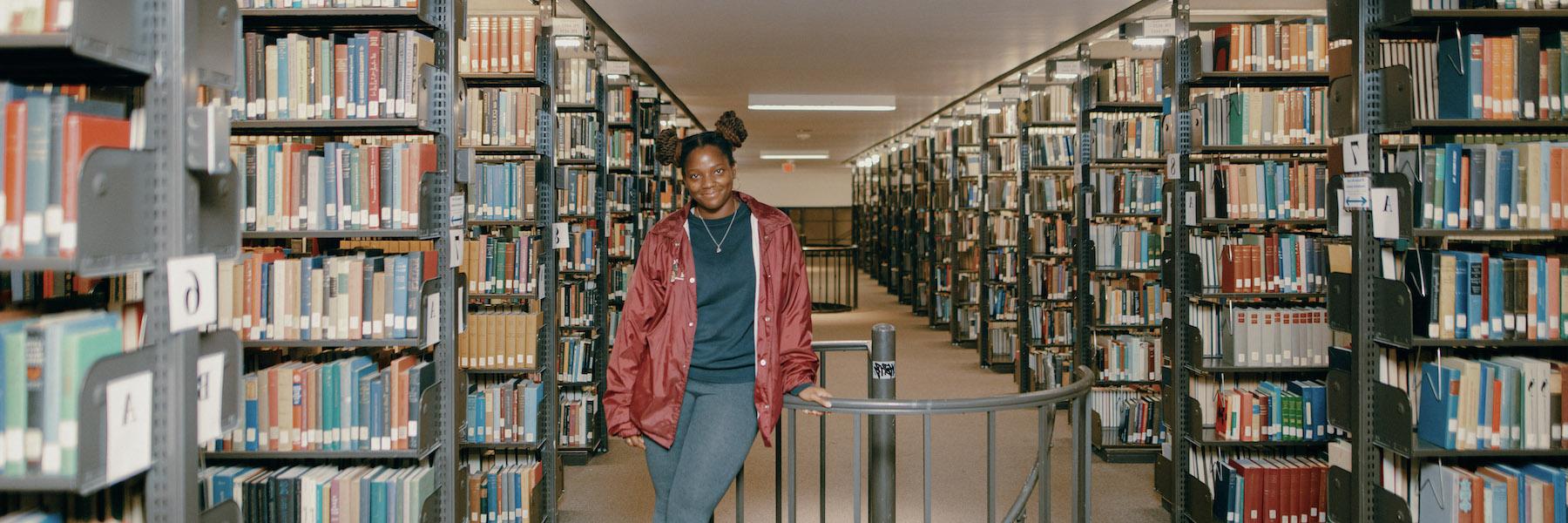 Student standing in library stacks