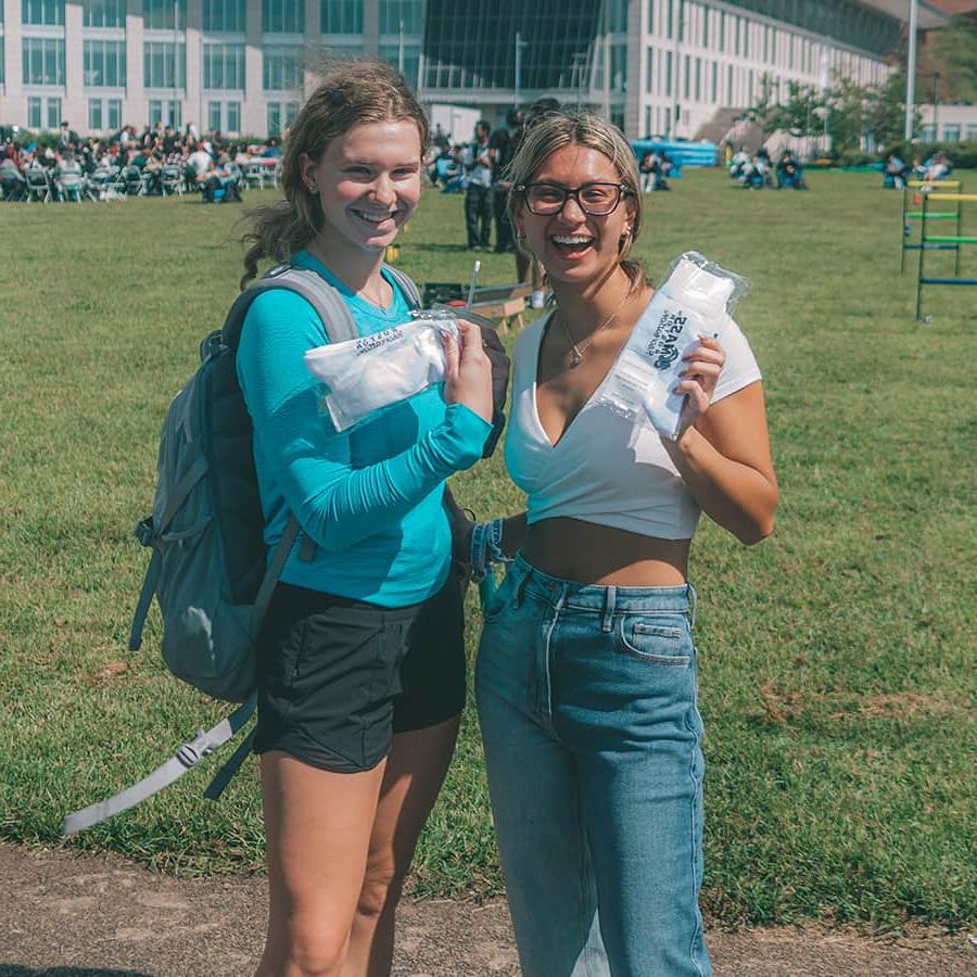Two students hold recreation swag socks on campus center lawn.