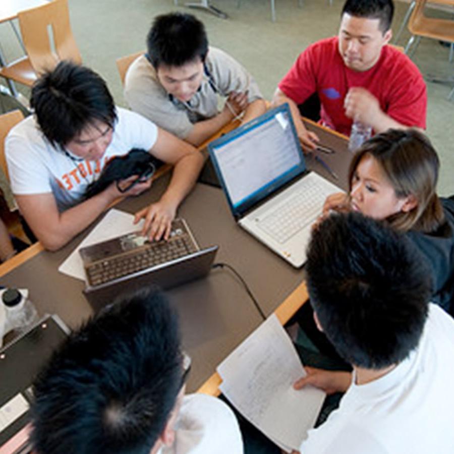 一群学生在自助餐厅用笔记本电脑工作.